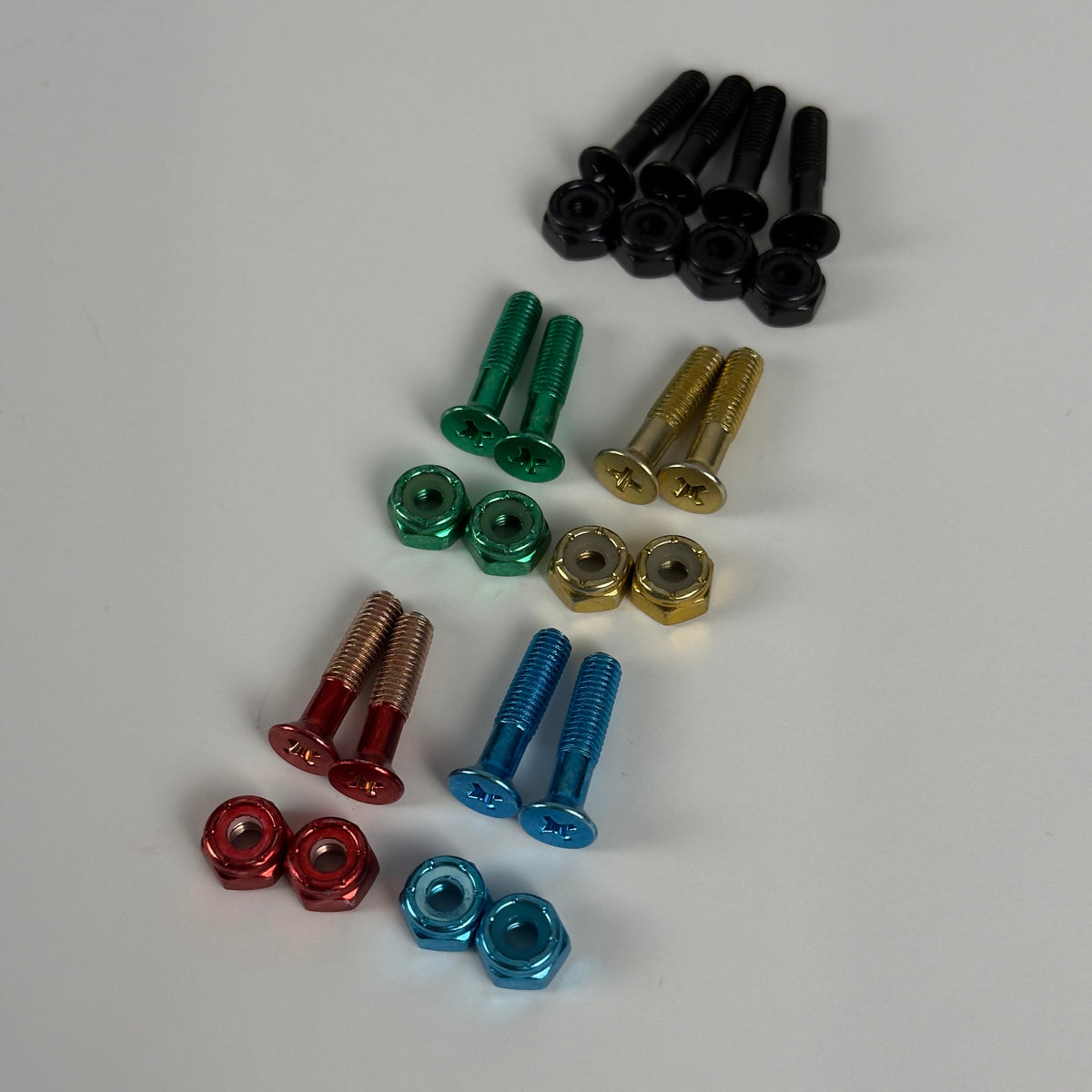 Colored skate bolts and nuts laid out by color: black, green, gold, red, and blue